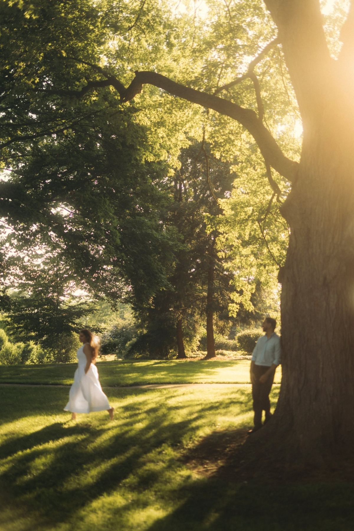 Arya crossing a sunlit lawn while Manthan leans on a tree, e-shoot styling and creative direction by Bhoomi Jani Weddings, Toronto