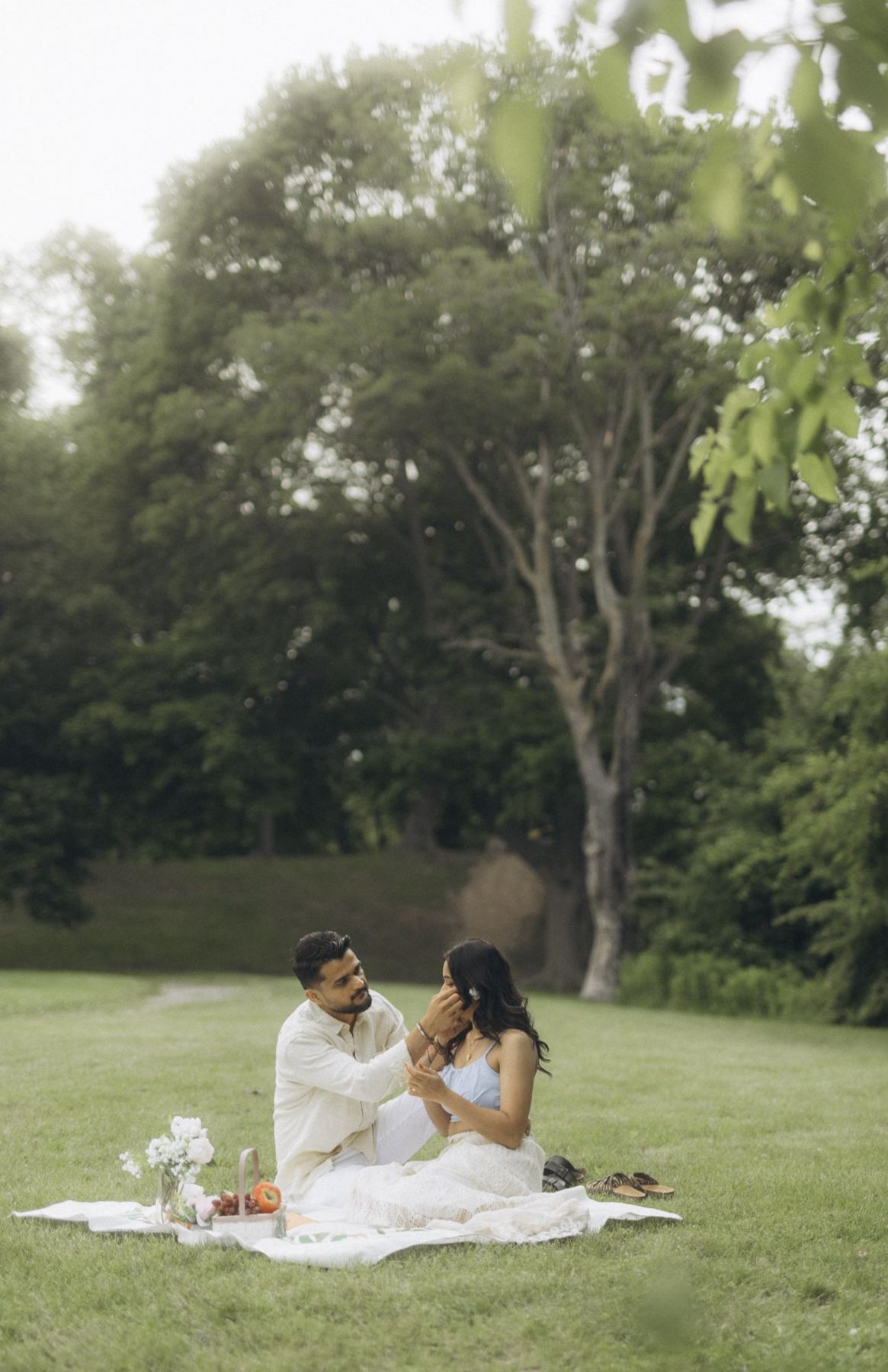 Rutva and Nitin on a picnic blanket beneath a tree, e-shoot styling by Bhoomi Jani Weddings
