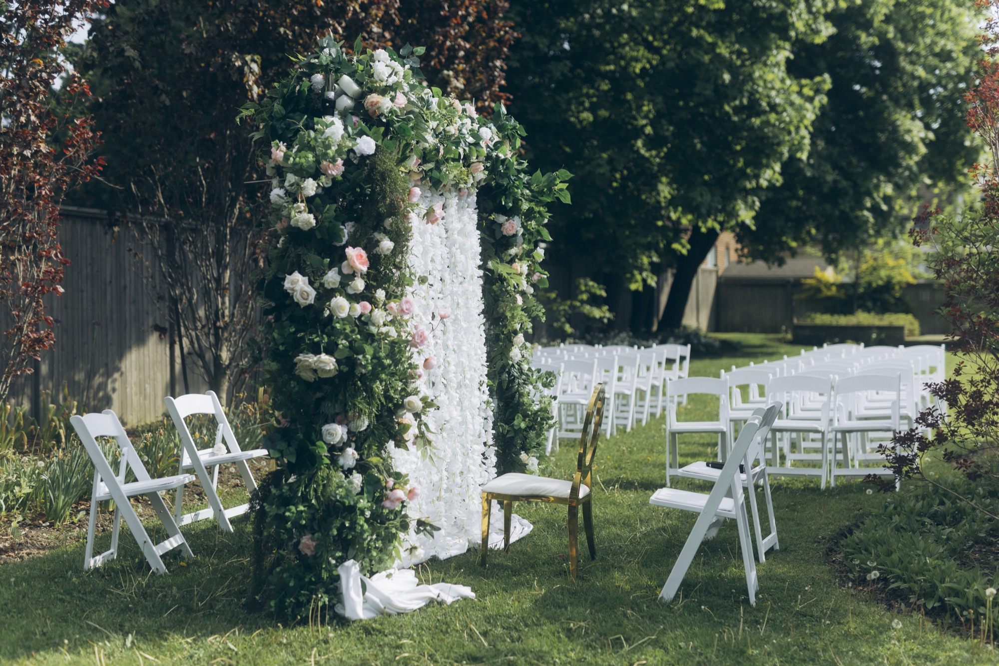 Floral ceremony arch and garden chairs set for an outdoor wedding, design and coordination by Bhoomi Jani Weddings, Greater Toronto Area