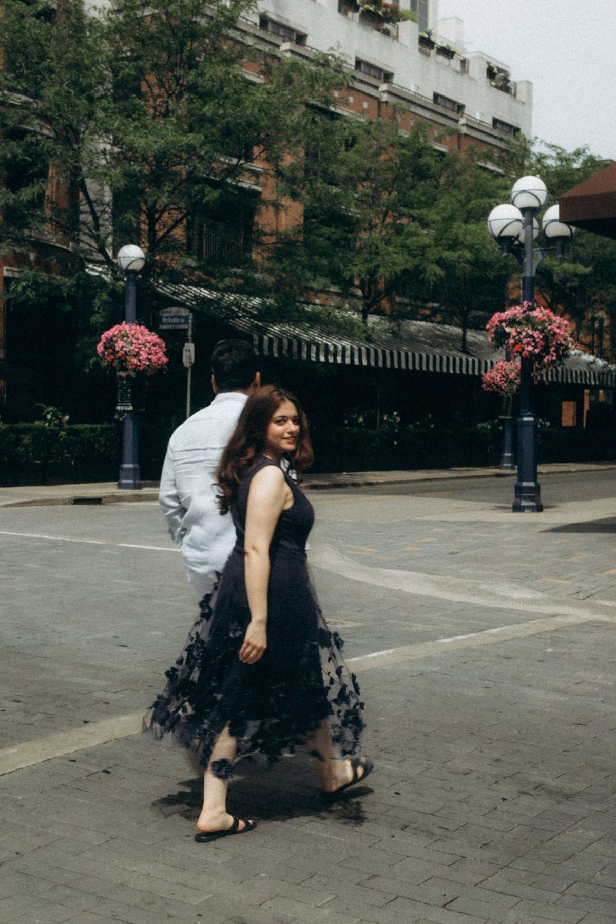 Manpreet in a black floral tulle dress crossing a Yorkville street, e-shoot styling by Bhoomi Jani Weddings